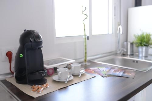 a coffee maker sitting on a kitchen counter with mugs at Ático, Studio 300 meters from Cathedral and Giralda in Seville
