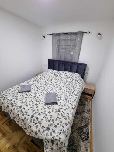 a bedroom with a bed with a comforter and a window at Apartman Sparta in Sombor