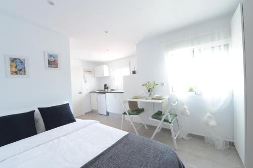 a white bedroom with a bed and a kitchen at Ático, Studio 300 meters from Cathedral and Giralda in Seville
