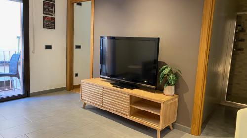 a flat screen tv sitting on top of a wooden entertainment center at Pequeño loft para dos in Sant Feliu de Guixols