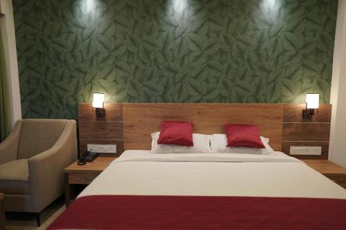 a bedroom with a large bed and a chair at HOTEL VKJ INN Aluva in Alwaye