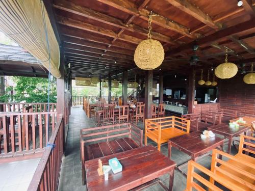 a restaurant with wooden benches and tables and chairs at PURI LESTARI in Sorongjukung