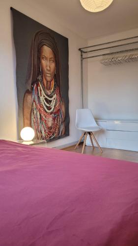 een groot schilderij van een vrouw aan een muur met een stoel bij Room in Marzili in Bern