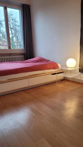 Schlafzimmer mit einem Bett, einem Fenster und einer Lampe in der Unterkunft Room in Marzili in Bern