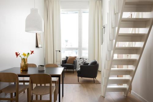 a living room with a table and chairs and a staircase at Noli Malmi in Helsinki