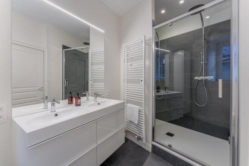 une salle de bain blanche avec un lavabo et une douche dans l'établissement Haxo - Superbe appt en centre ville pour 7, à Nantes