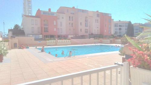 - une piscine avec des personnes devant un bâtiment dans l'établissement Grand T3 piscine, garage centre port, au Cap d'Agde