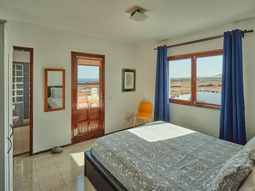 a bedroom with a bed with blue curtains and a window at Playa Marina Eco Beach Villa in Arrieta