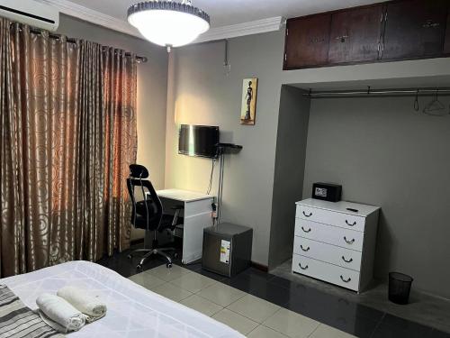 a bedroom with a bed and a desk and a bed and a chair at TRMOTEL in Matola