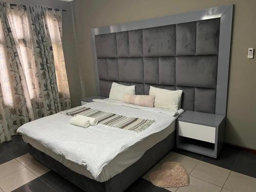 a bedroom with a large bed with a gray headboard at TRMOTEL in Matola