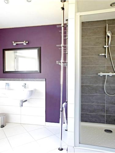 La salle de bains est pourvue d'un lavabo et d'une porte de douche en verre. dans l'établissement Maison charmante à Plouégat-Moysan avec spa, à Plouégat-Moysan