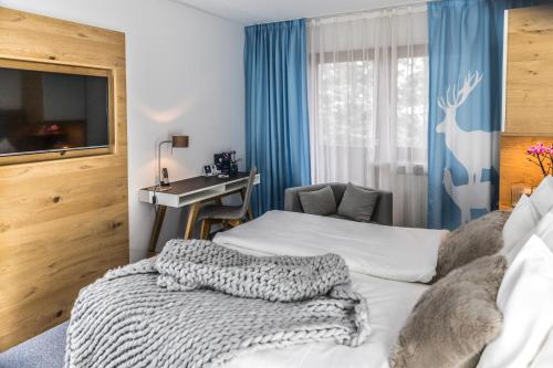 a hotel room with a bed and a desk and a window at Das Aunhamer Suite & Spa Hotel in Bad Griesbach