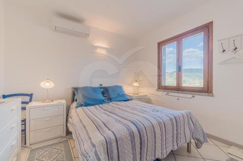 a white bedroom with a bed and a window at Il Porto 25 Mansarda sul Mare - Goelba in Porto Azzurro