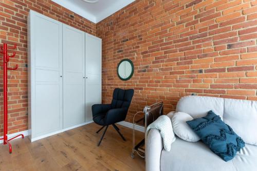 ceglana ściana w pokoju z kanapą i krzesłem w obiekcie Apartamenty Villa Petsch - w sercu Cieplic - by Space Apart w Jeleniej Górze