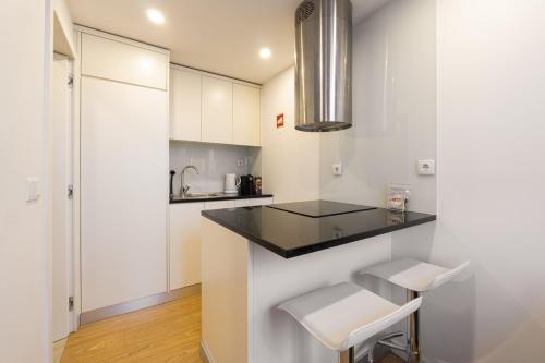 a kitchen with white cabinets and a counter and stools at GuestReady - King House 3 in Porto
