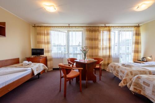 Habitación de hotel con 2 camas, mesa y sillas en OW Carbo w sąsiedztwie lasu i jeziora, en Dąbki