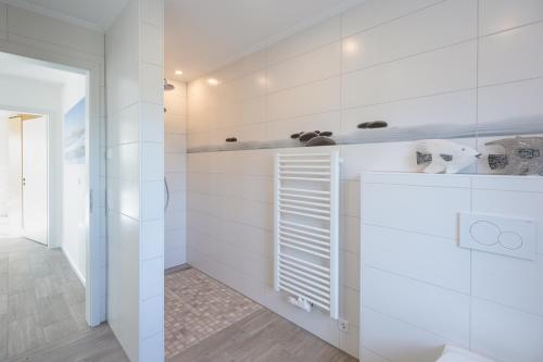 a white bathroom with white walls and a window at Achtern Diek in Dagebüll