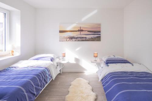 ダゲビュルにあるBi uns to Husの白い部屋のベッド2台 壁に絵画が飾られています。