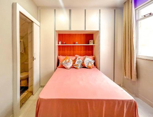 a bedroom with a large pink bed with three pillows at Ótimo studio c WiFi a 190m da Praia do Leme - RJ in Rio de Janeiro