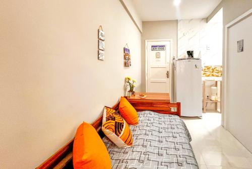 a bedroom with a bed with orange pillows and a refrigerator at Ótimo studio c WiFi a 190m da Praia do Leme - RJ in Rio de Janeiro