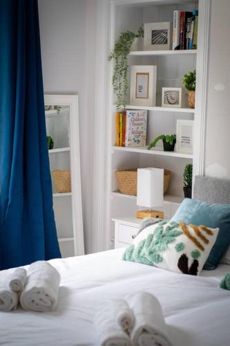 a bedroom with a white bed and a book shelf at Linburn Cottage Dunfermline near Edinburgh in Dunfermline