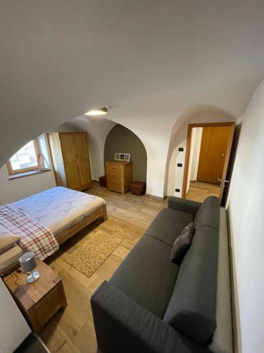 ein Wohnzimmer mit einem Sofa und einem Bett in der Unterkunft Appartamento Gioia di Bosco in Carano