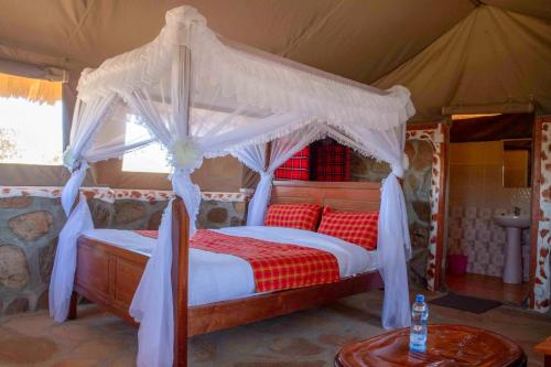 een slaapkamer met een hemelbed in een tent bij Orng'atuny Mara King Camp in Masai Mara