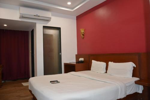 - une chambre avec un lit blanc et un mur rouge dans l'établissement The Grand Neelam, à Phundardih