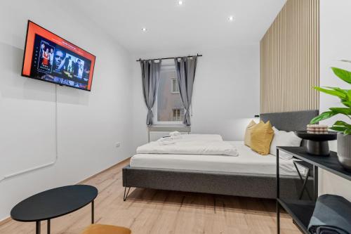 a bedroom with a bed and a tv on a wall at Frisch renovierte Wohnung - Zentral/Ruhig/Modern in Augsburg