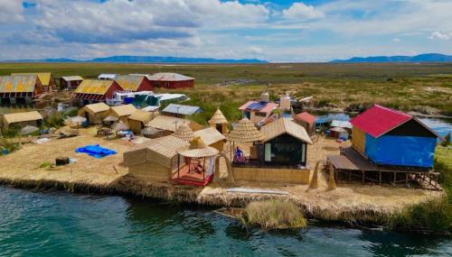 un groupe de huttes sur une île dans l'eau dans l'établissement TITICACA WORLDWIDE LODGE, à Puno