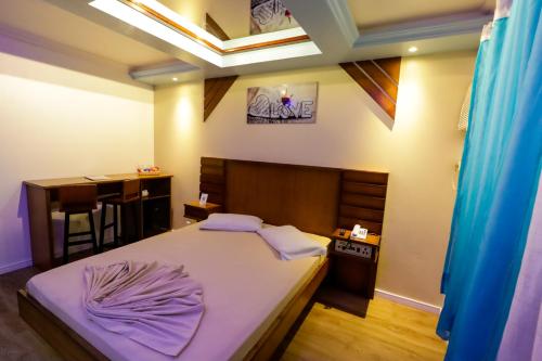 um quarto com uma cama com lençóis roxos e uma secretária em Motel Avenida (Adult Only) em Gramado