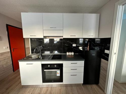 a kitchen with white cabinets and a stove top oven at BELLAVISTA APARTMENT in Passo del Tonale