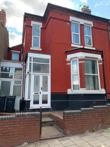 Casa de ladrillo rojo con ventanas blancas y escaleras en Handsworth Hostel - Stay Sleep Rest en Birmingham