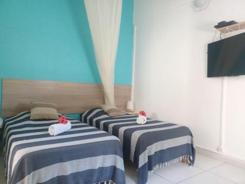 two beds in a room with blue and white stripes at La Rose du Bresil Marie-Galante in Capesterre-de-Marie-Galante