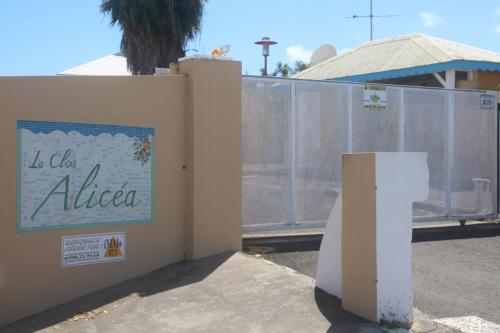 un muro con un cartello sopra accanto a una recinzione di les Aliceas appartement cosy a Baie-Mahault