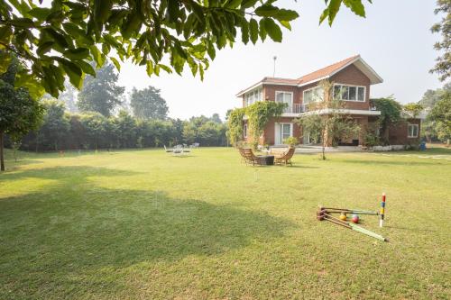 a large yard with a house with at Hostie Humming Trees - 4BHK Farm house, Opp Westin Sohna in Sohna