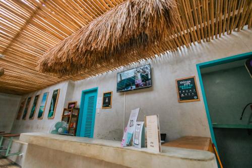 a restaurant with a counter with a menu and a straw roof at Mad Monkey Hostel Nacpan Beach in El Nido