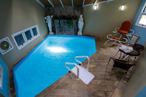 a swimming pool in a house with chairs around it at Motel Avenida (Adult Only) in Gramado