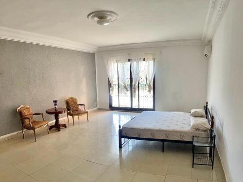 a bedroom with a bed and two chairs and a table at La Villa Maria in Dakar