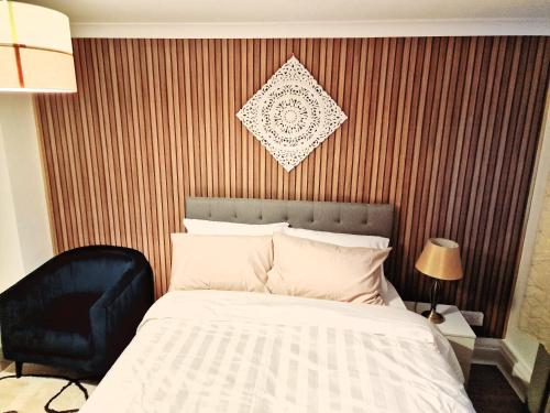 a bedroom with a bed and a black chair at Flat 16 Homedale house in Sutton