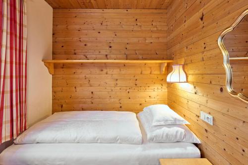 a bed in a room with a wooden wall at Appartementhaus Holiday in Lech am Arlberg
