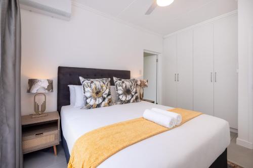 a bedroom with a white bed with a black headboard at Ballito Village Luxury Apartments in Ballito
