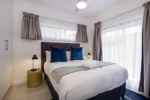 a bedroom with a large bed with blue pillows at Ballito Village Luxury Apartments in Ballito