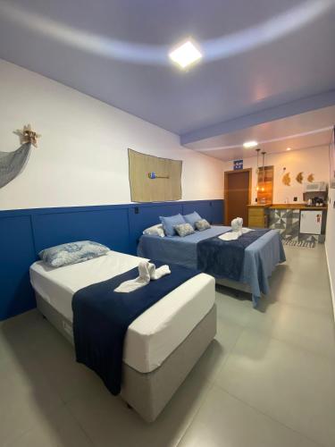 two beds in a room with blue walls at Pousada Águas da Grota in Penha