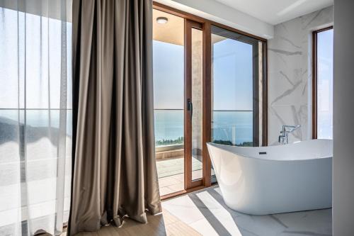 a bathroom with a tub and a large window at Cape Montenegro Villas in Krimovice