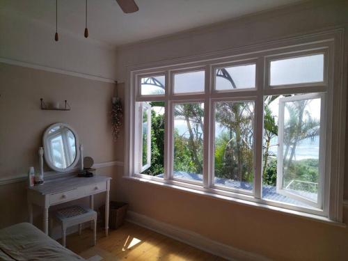 a bedroom with a window with a mirror and a table at Sunrise beach house in Kingsburgh
