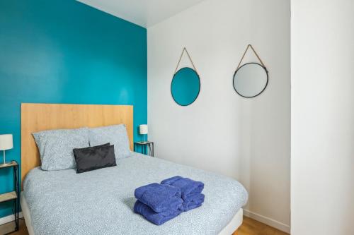 a bedroom with a bed with blue walls and mirrors at Aux portes de Paris Cozy - Proche Métro L3 L9 in Bagnolet