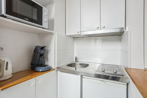 a white kitchen with a sink and a microwave at Aux portes de Paris Cozy - Proche Métro L3 L9 in Bagnolet