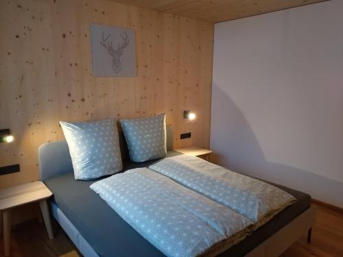 Schlafzimmer mit einem Bett mit blauer Bettwäsche und Kissen in der Unterkunft Fuxrevier in Schoppernau