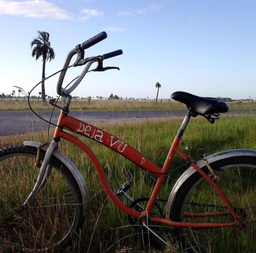 una bici rossa parcheggiata nell'erba in un campo di Deja vu a Barra de Valizas